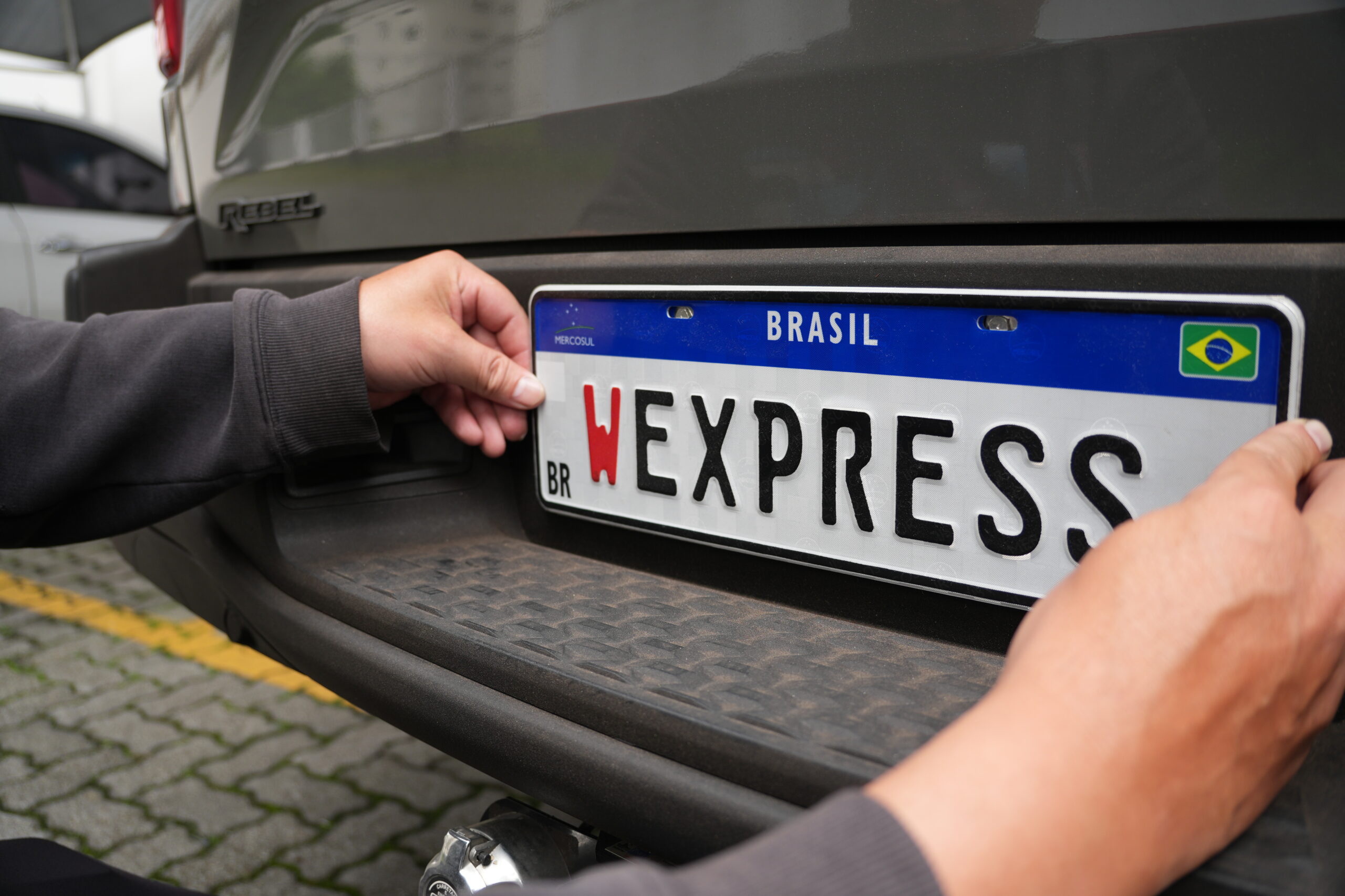 Técnico trocando a placa de um veículo, representando os desafios e processos burocráticos do emplacamento.