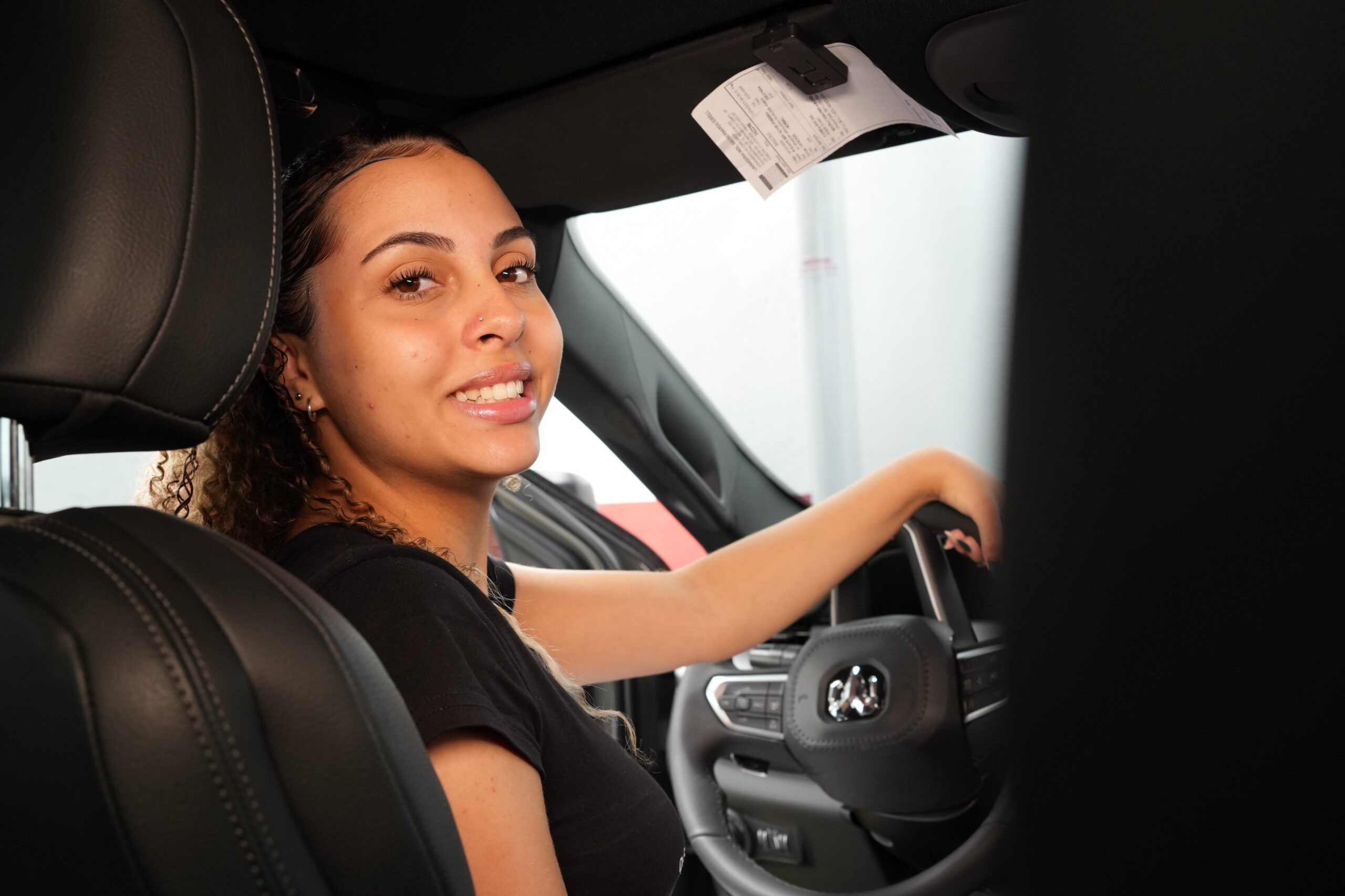 Jovem dirigindo carro 0KM recém-comprado ainda sem emplacamento, representando riscos por desconhecer mitos que podem causar multa.